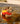 Brown dog wearing bright orange and yellow dog life jacket while standing in shallow lake water for safe swimming and outdoor fun.