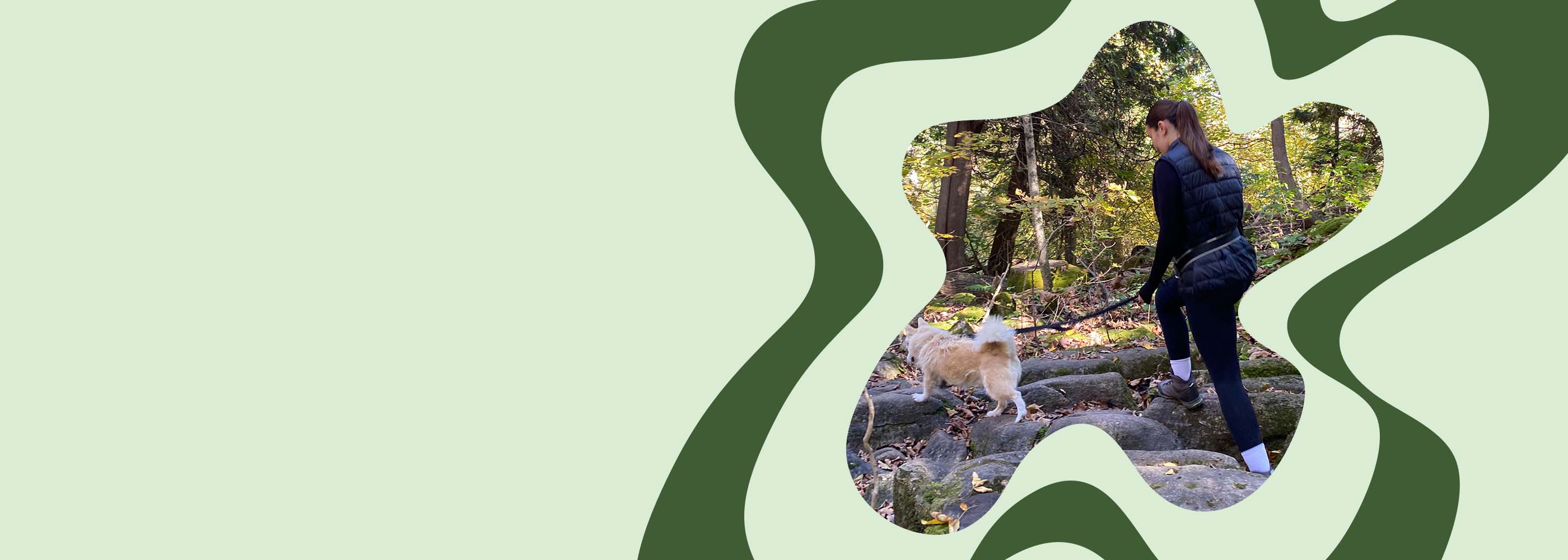 Woman hiking forest trail with dog using a hands-free dog leash for safe, comfortable outdoor adventure.