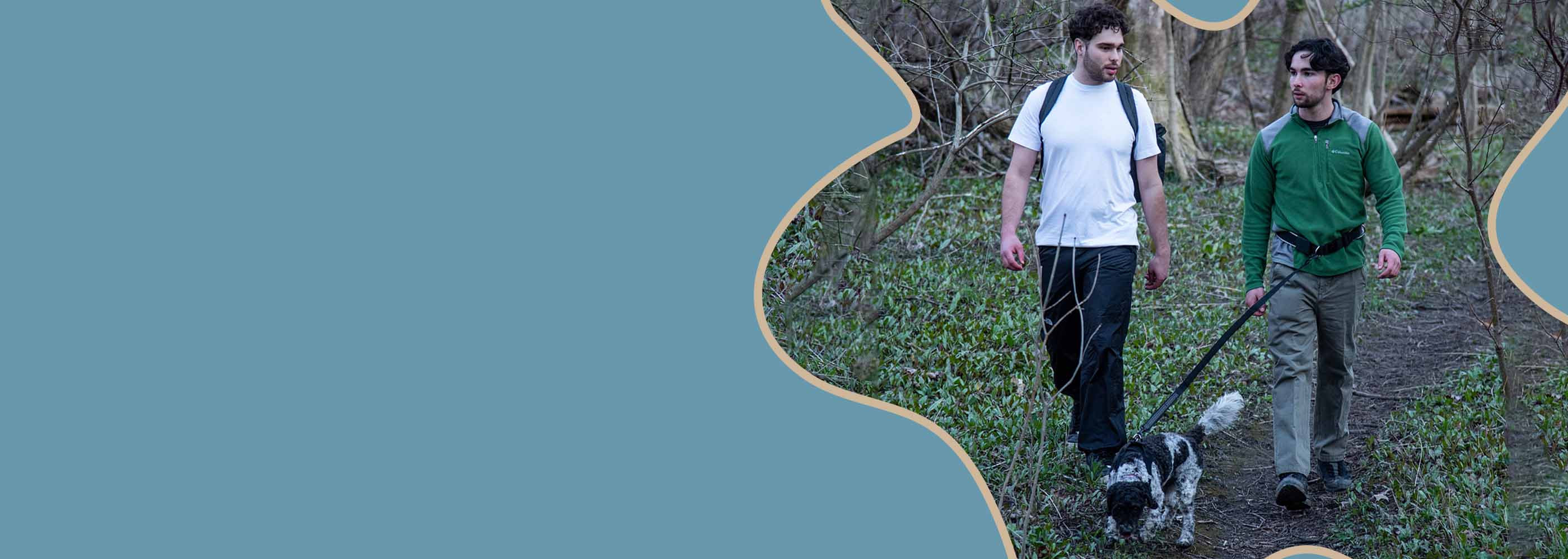 Two men hiking forest trail with dog using a black hands-free dog leash for safe outdoor walking.